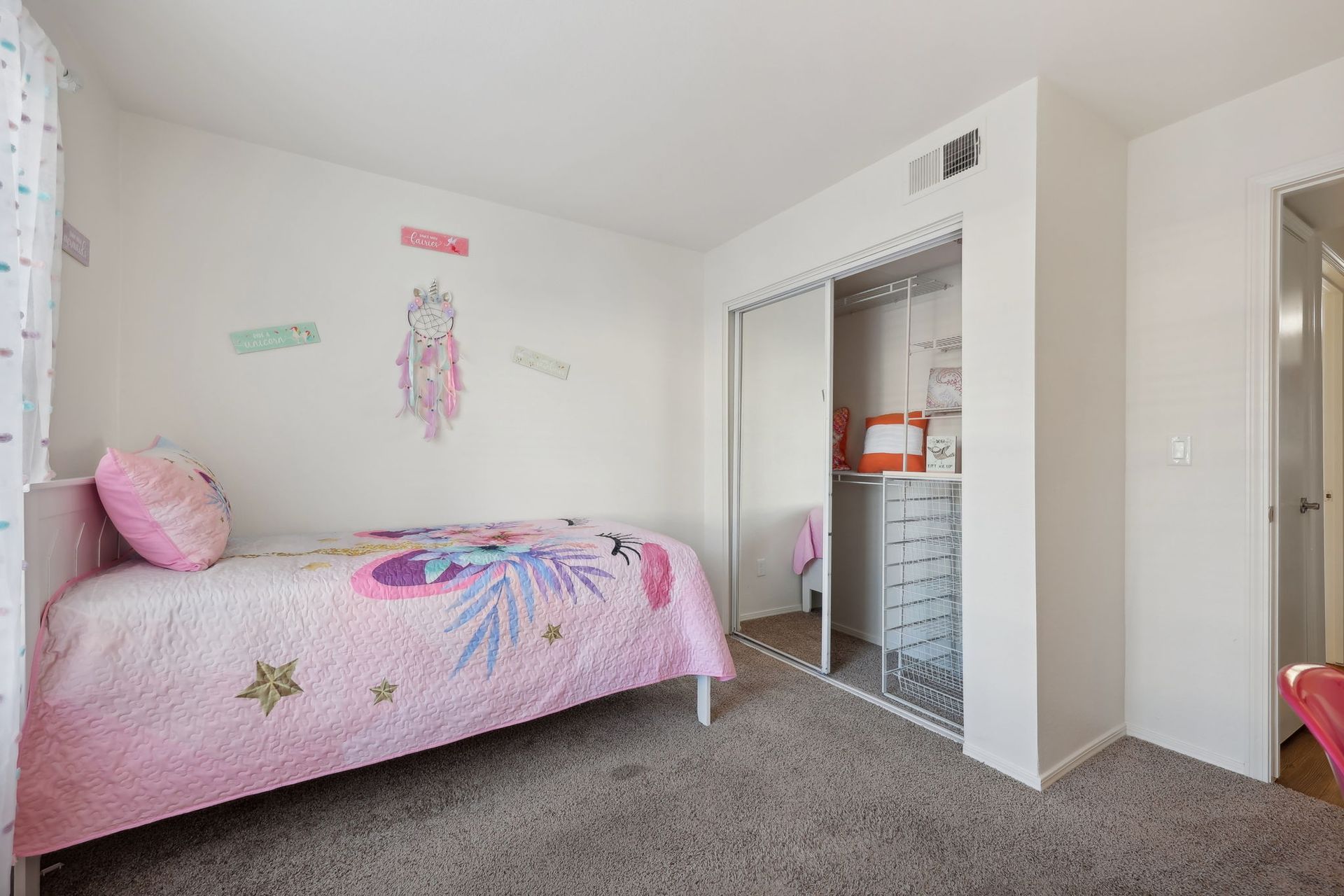 Bedroom with a bed, closet with sliding doors, and a pink bedspread.