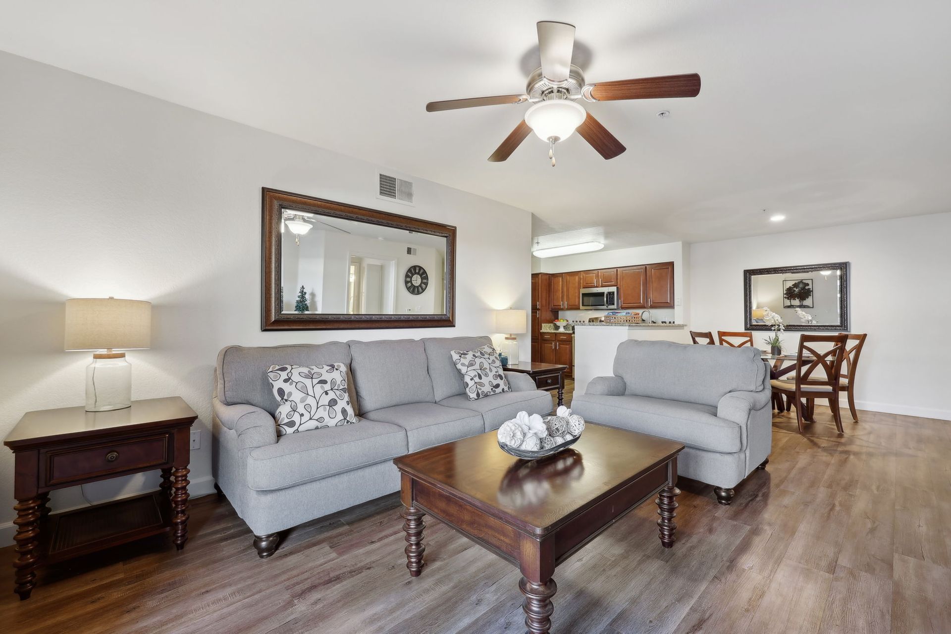 Living room with gray sofa, chair, dark wood furniture, and dining area.