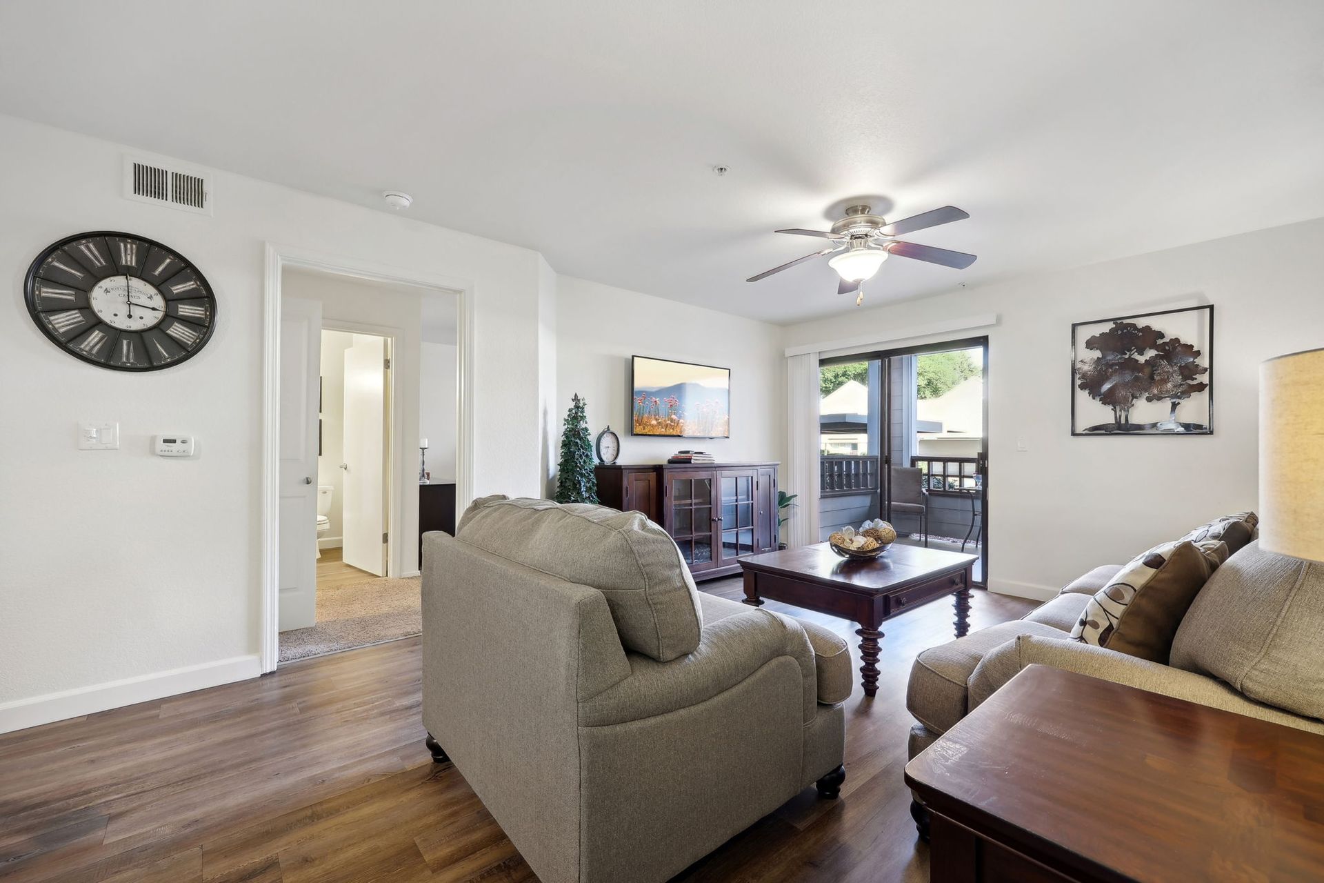 Living room with beige furniture, TV, coffee table, and sliding door to a balcony.