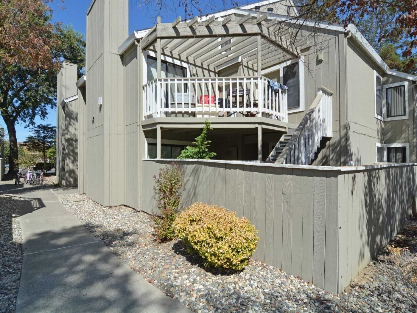 Gray townhouse exterior with wooden fence, patio, and walkway.