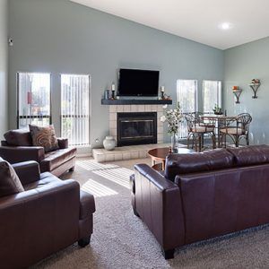 Living room with brown leather furniture, fireplace, and dining area. Blue-green walls.