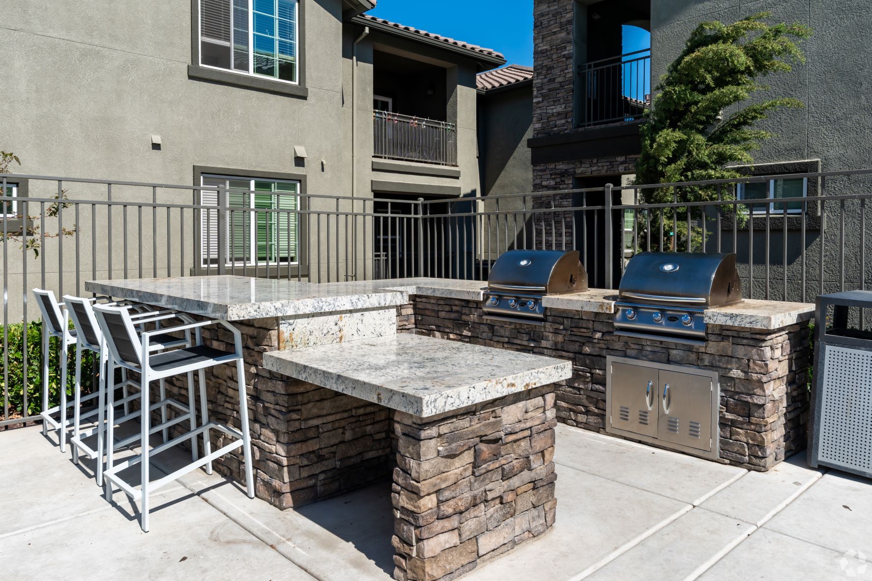 Outdoor grilling area with two grills, granite counters, and seating.