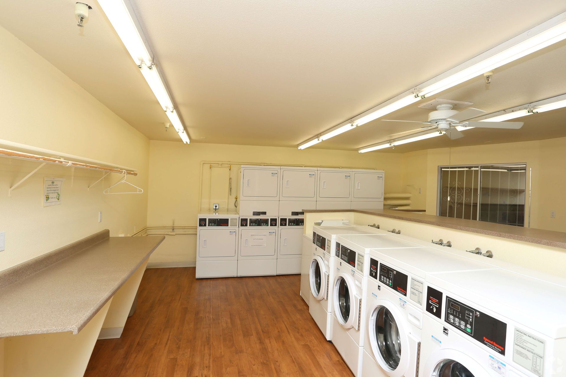 Laundry room with several washing machines, folding tables, and overhead lighting.