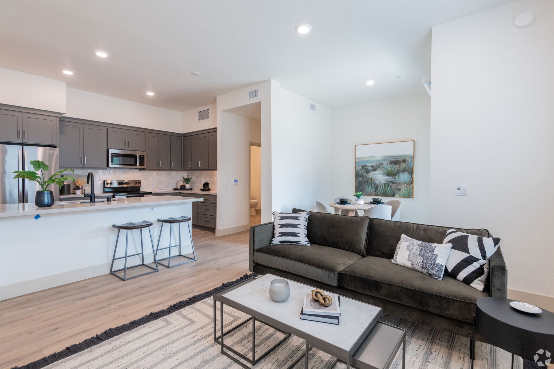 Modern living room with kitchen, sofa, coffee table, and dining area.