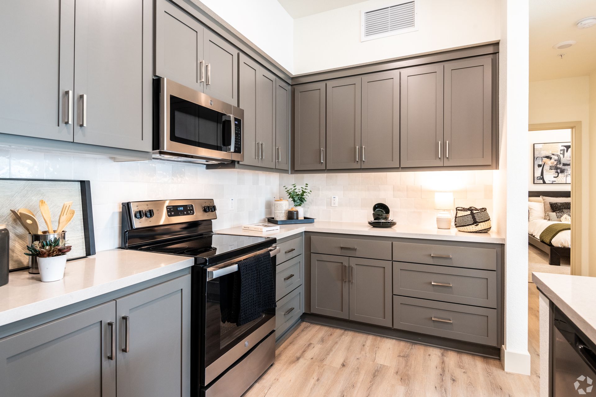 Gray kitchen cabinets with stainless steel appliances and white countertops.