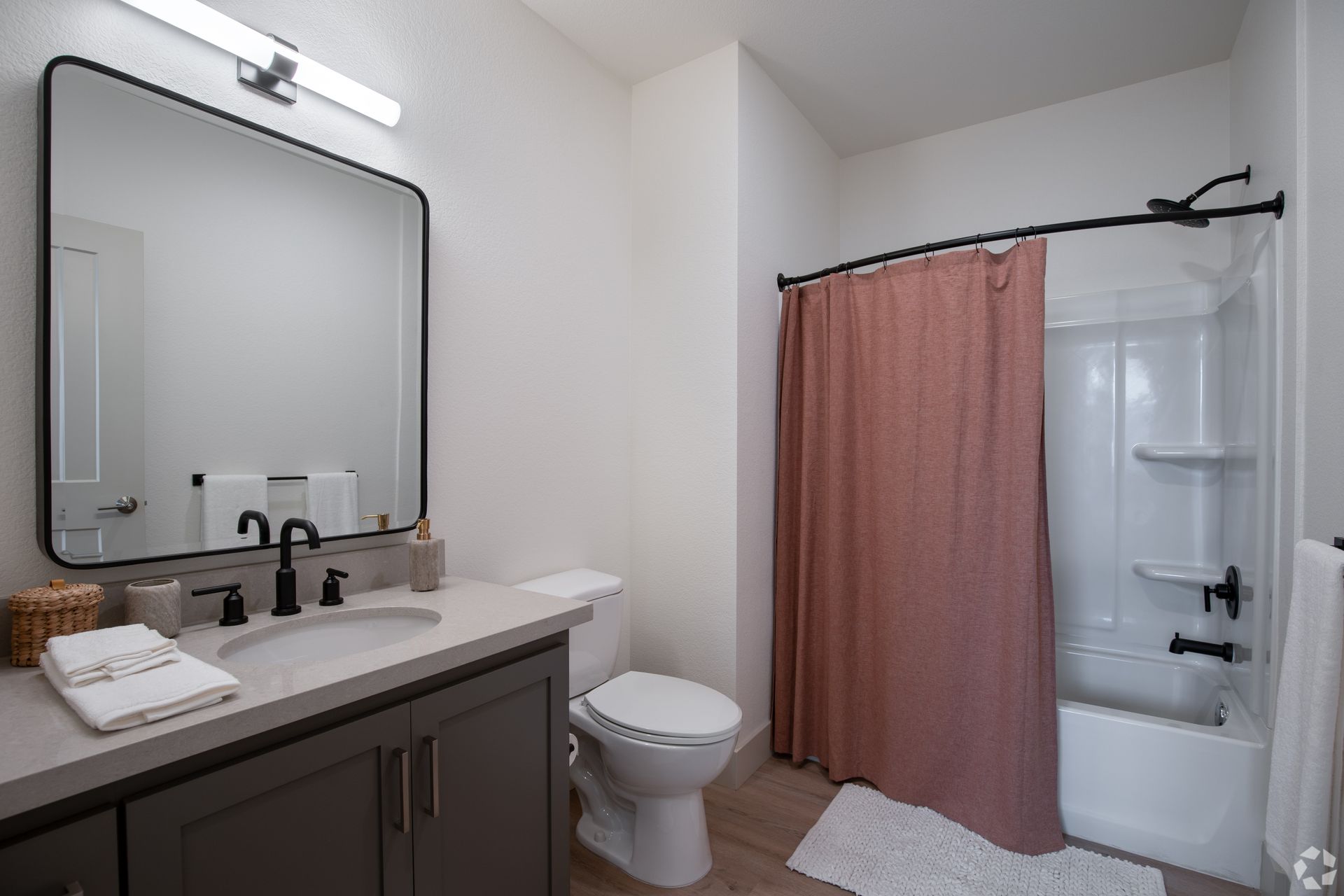 Bathroom with a gray vanity, white toilet, pink shower curtain, and a large mirror.