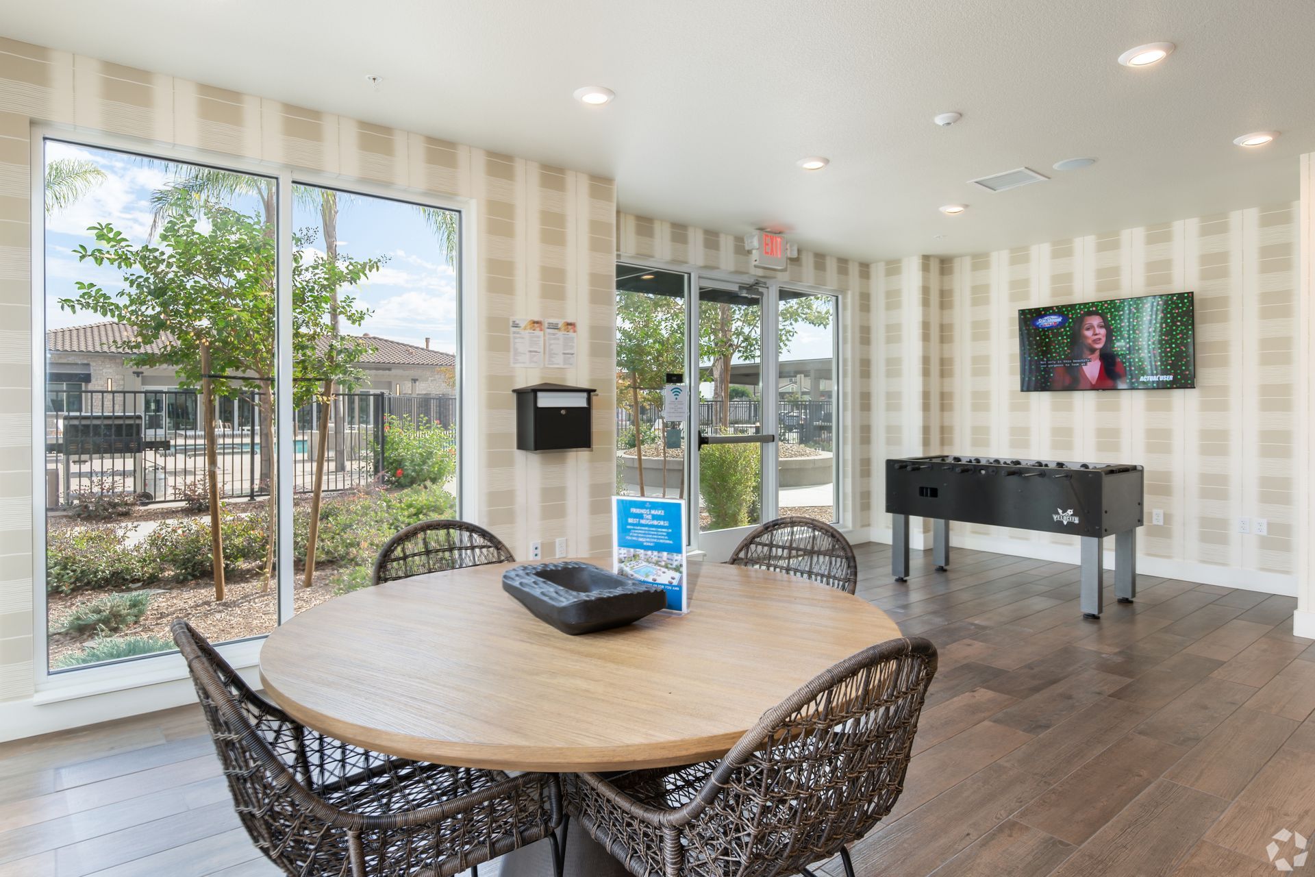 Game room with a round table, chairs, foosball table, TV, and large windows.