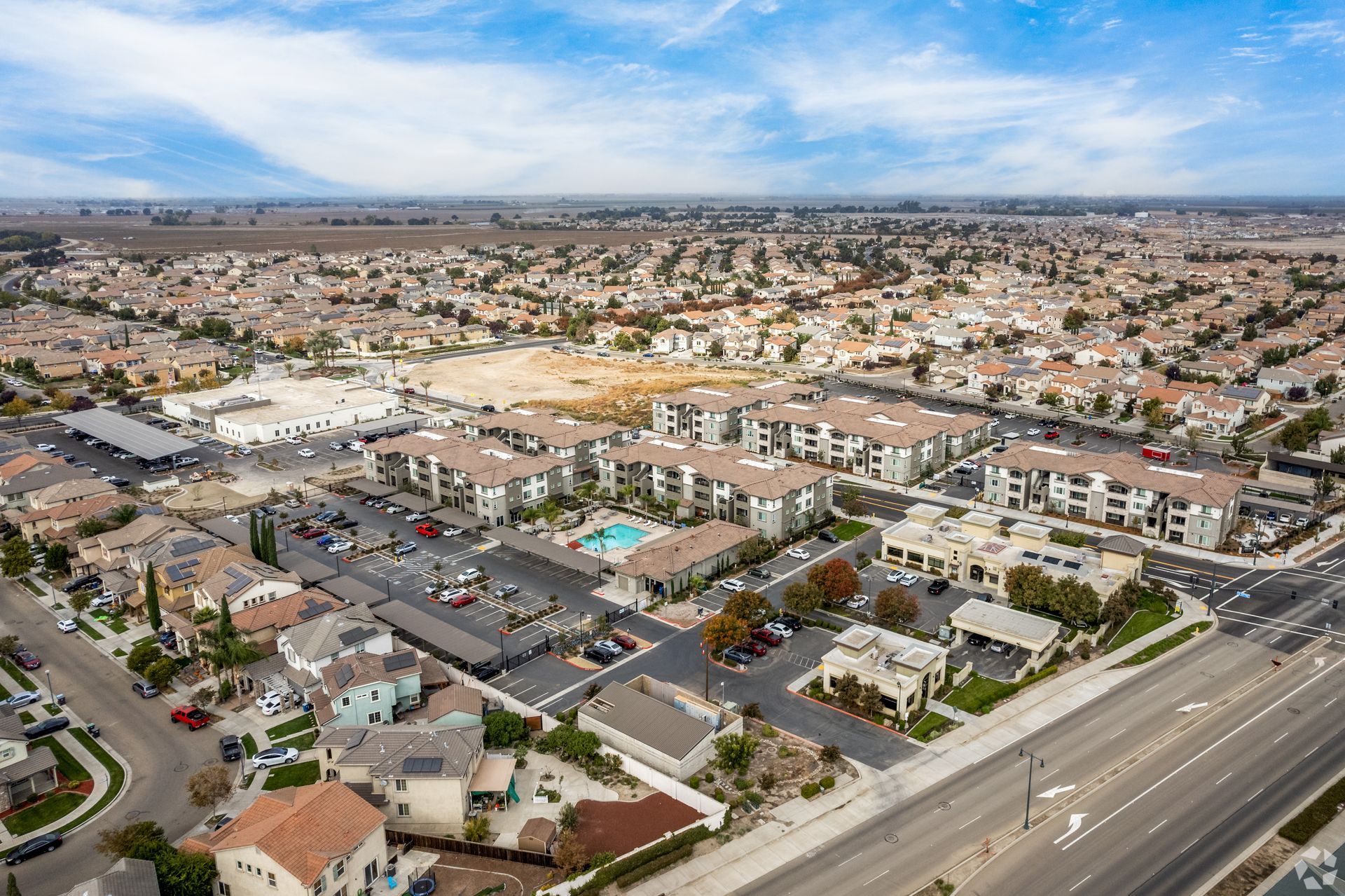 Aerial view of a suburban neighborhood with apartment buildings, a shopping center, and roads.
