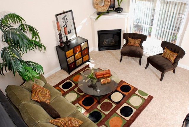 Living room with green sofa, brown chairs, fireplace, and patterned rug.