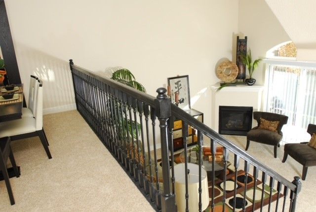 Overhead view of a living room with a black railing, fireplace, chairs, and decor.