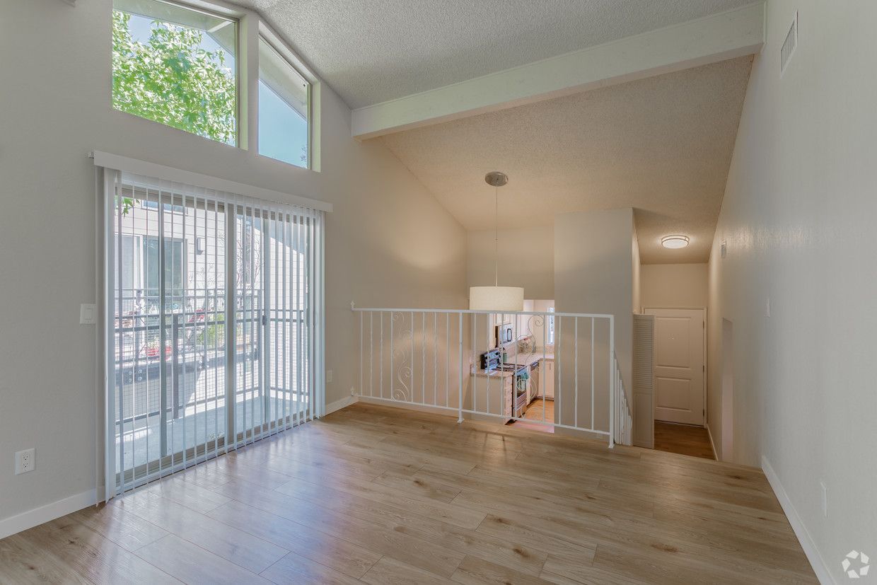 Bright living room with loft, sliding glass door to balcony, and light wood floors.