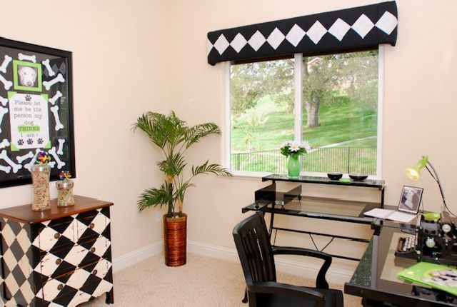 Office with a desk, window, checkered accents, and a large plant.