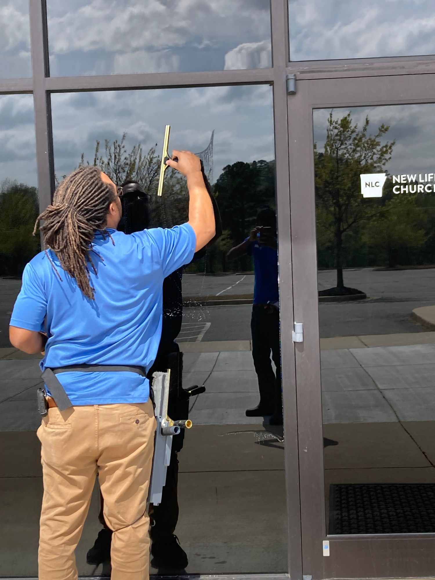 A man in a blue shirt is cleaning a glass door