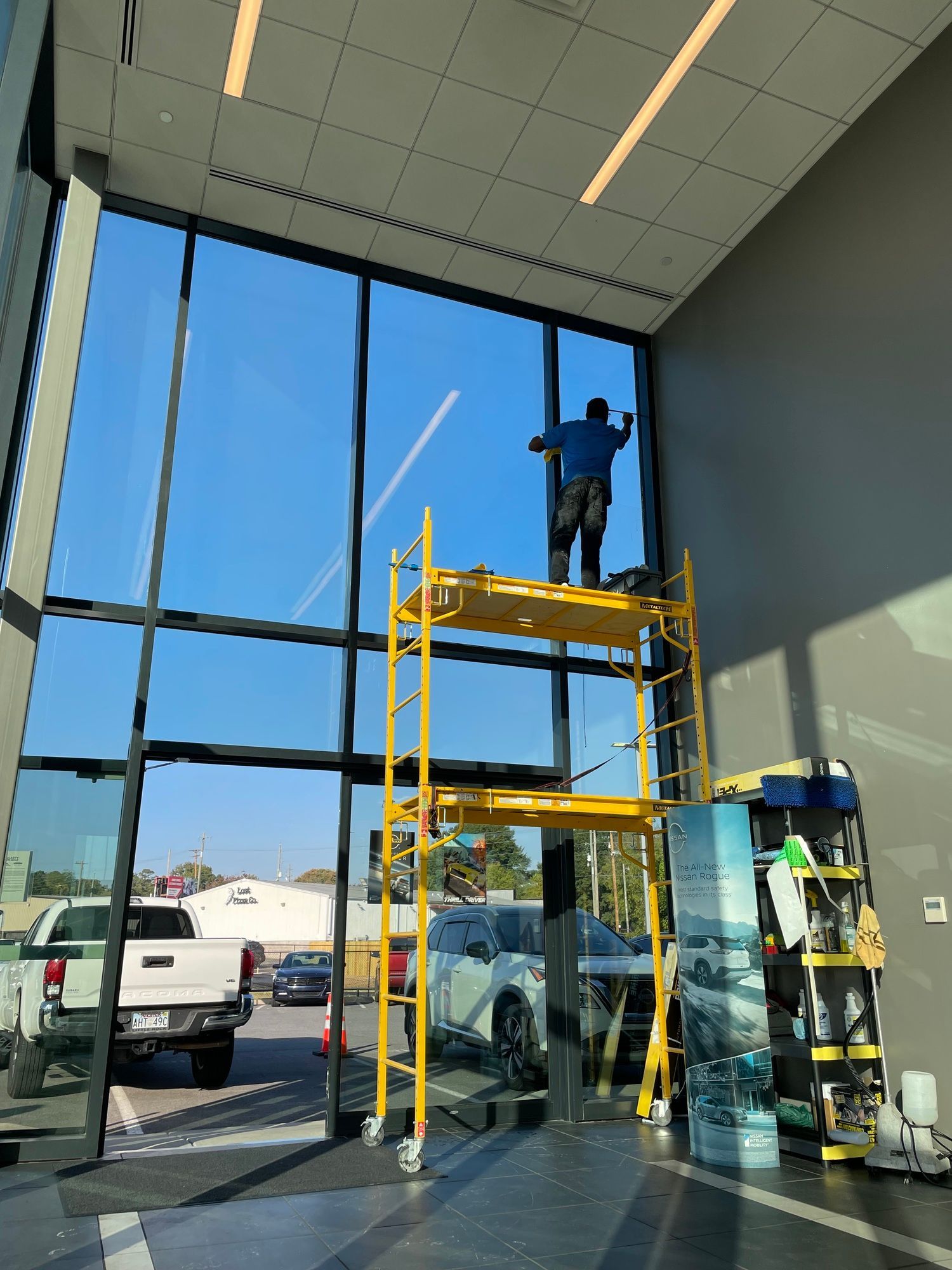 A man is standing on a scaffolding cleaning a window