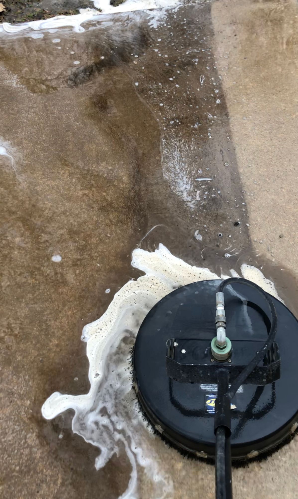 A pressure washer is being used to clean a concrete floor.