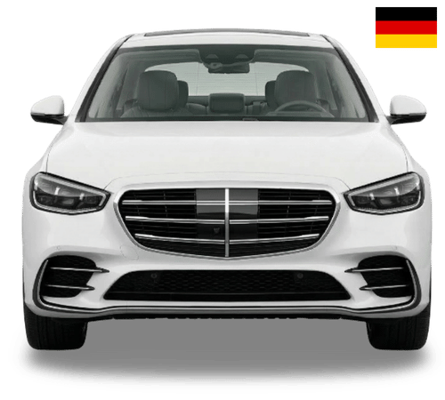 A front-facing white Mercedes-Benz S-Class sedan with a small German flag icon in the top right corner.