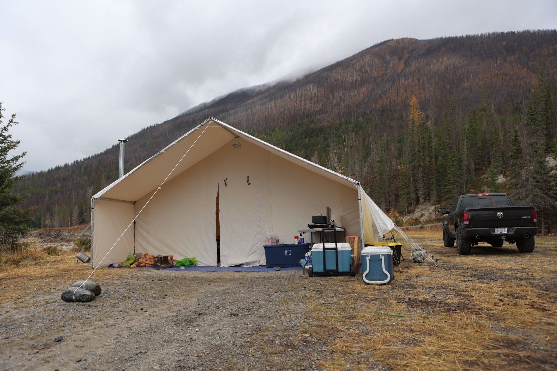 A truck is parked in front of a tent with mountains in the background