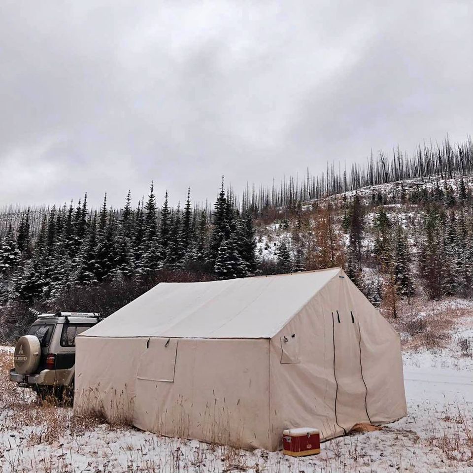 A tent is sitting in the middle of a snowy field