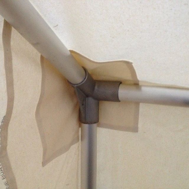 A corner of a tent with a metal pipe attached to it
