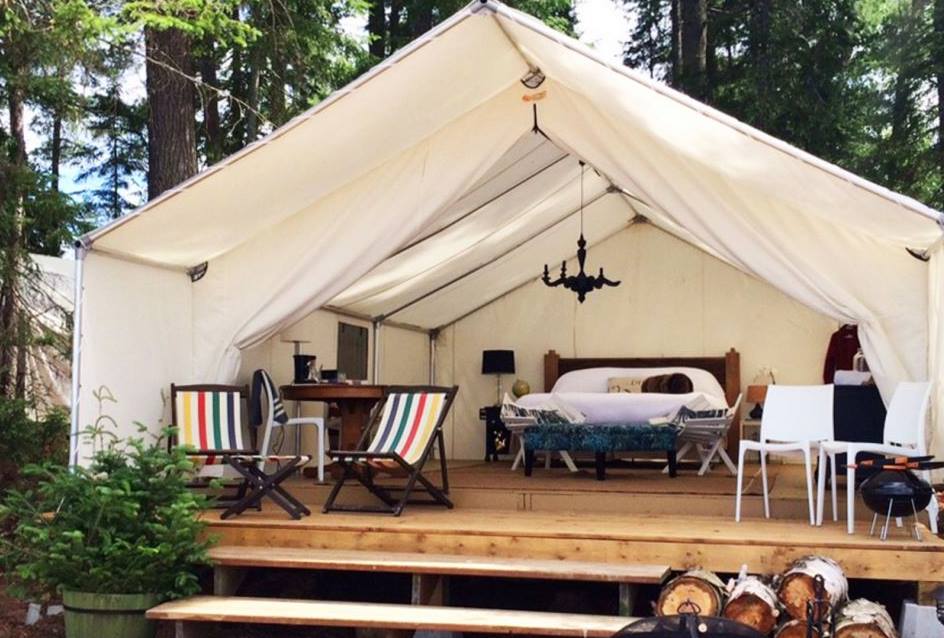 A tent with a bed and chairs inside of it