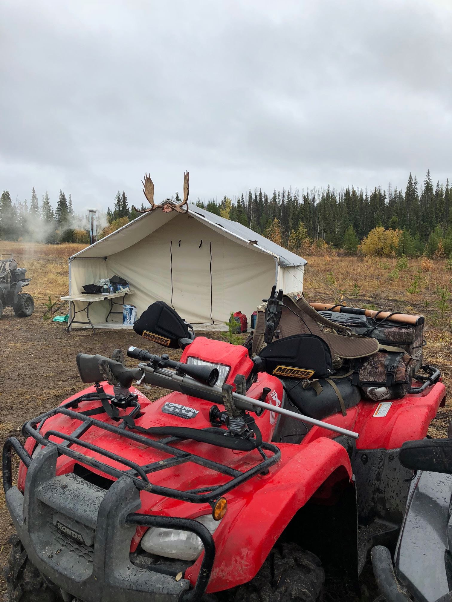 A red atv is parked in a field in front of a tent.