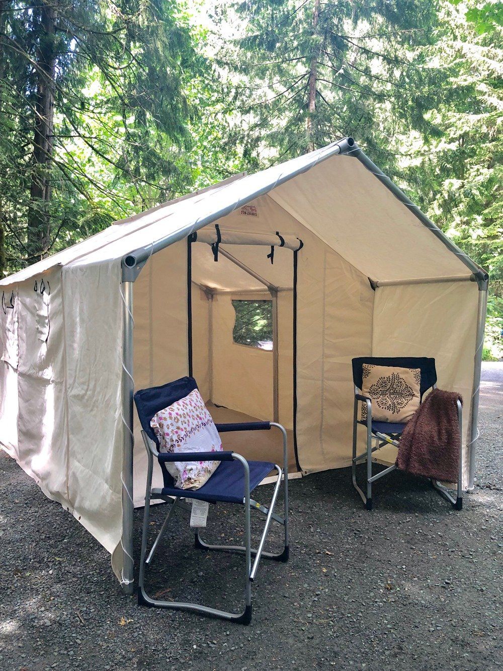 A tent with a chair and a blanket in front of it.