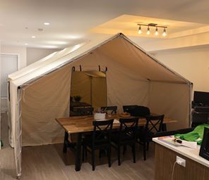 A dining room with a table and chairs under a tent.