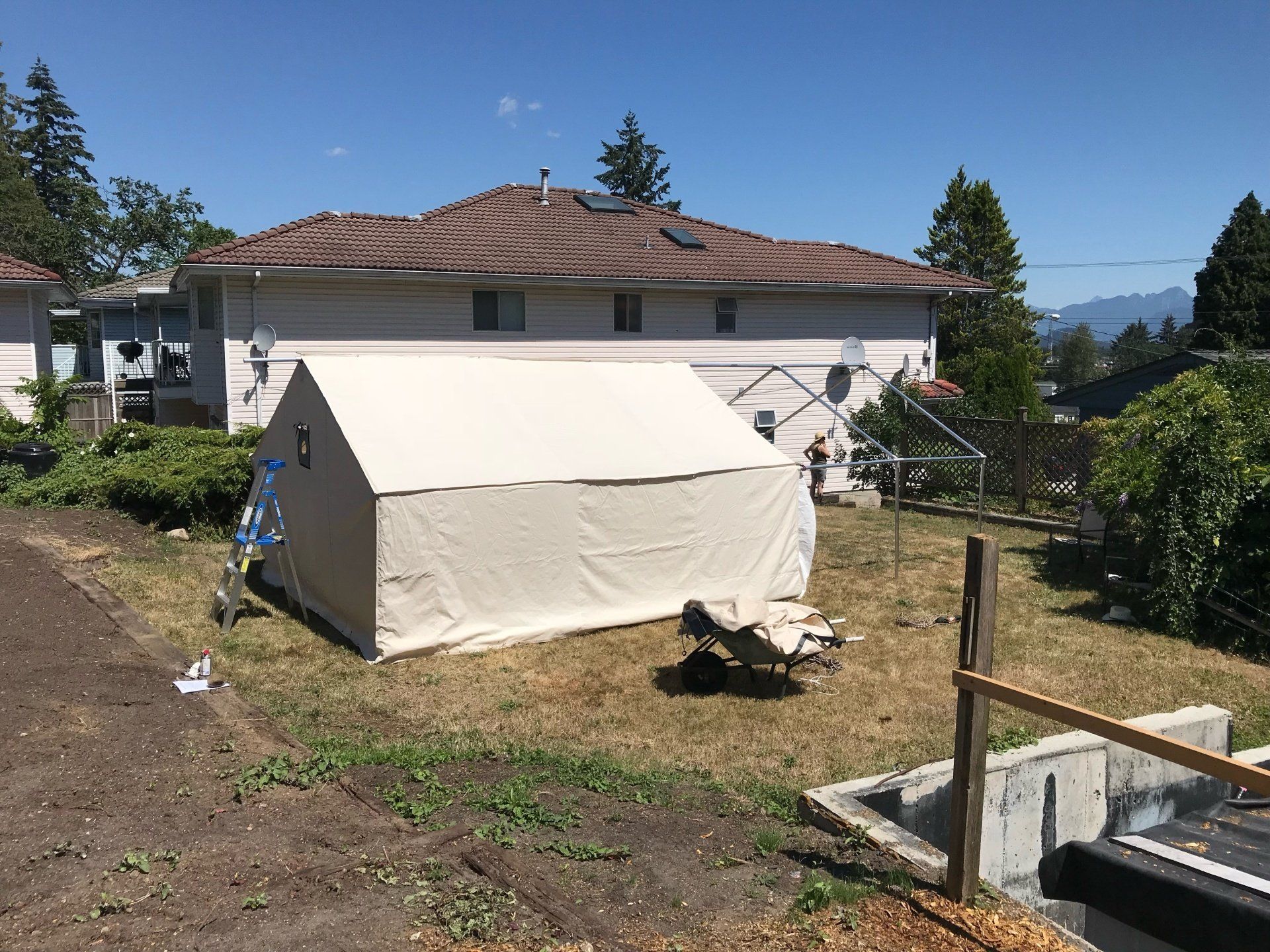A white tent is sitting in the backyard of a house.