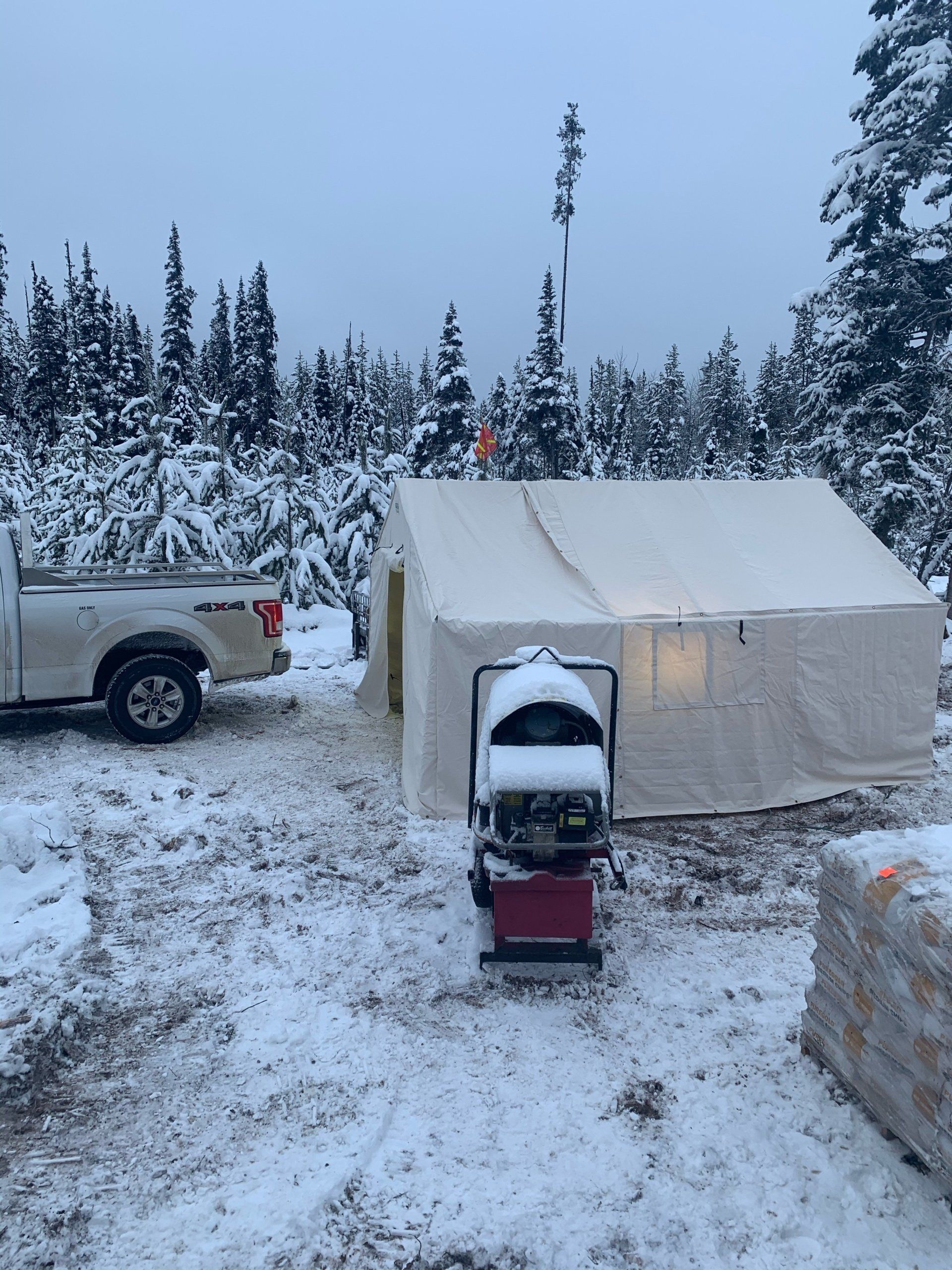 A truck is parked next to a tent in the snow