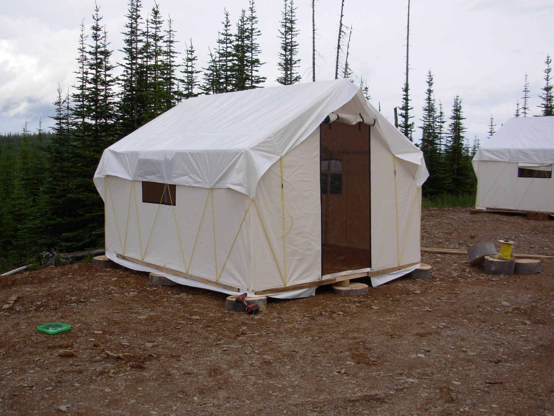 A white tent is sitting in the middle of a dirt field
