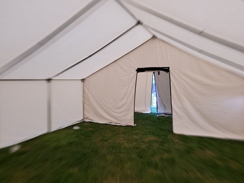 A white tent is sitting on top of a lush green field