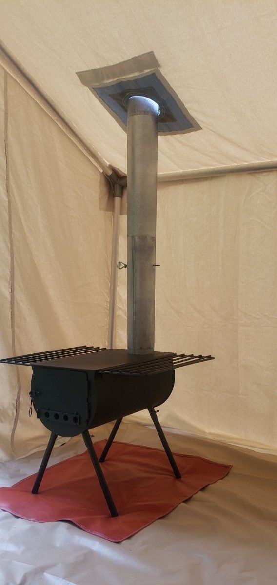 A small stove is sitting on a red mat in a tent.