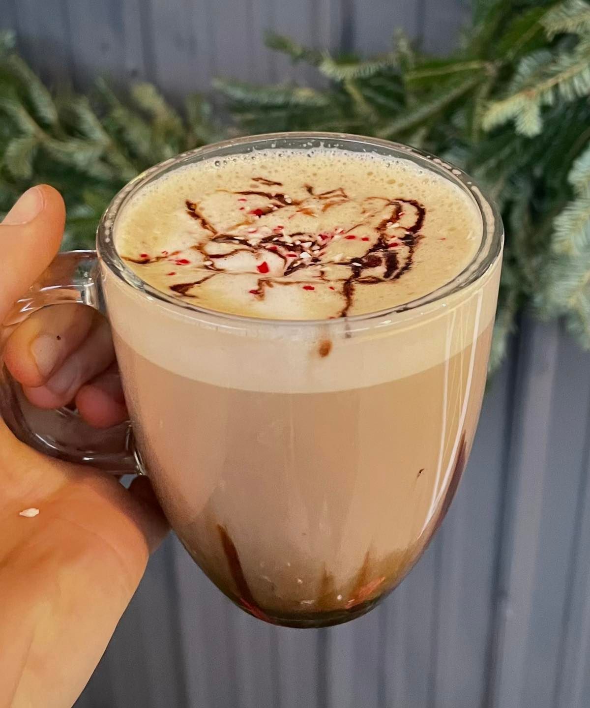 A person is holding a cup of coffee with whipped cream and chocolate shavings on top.