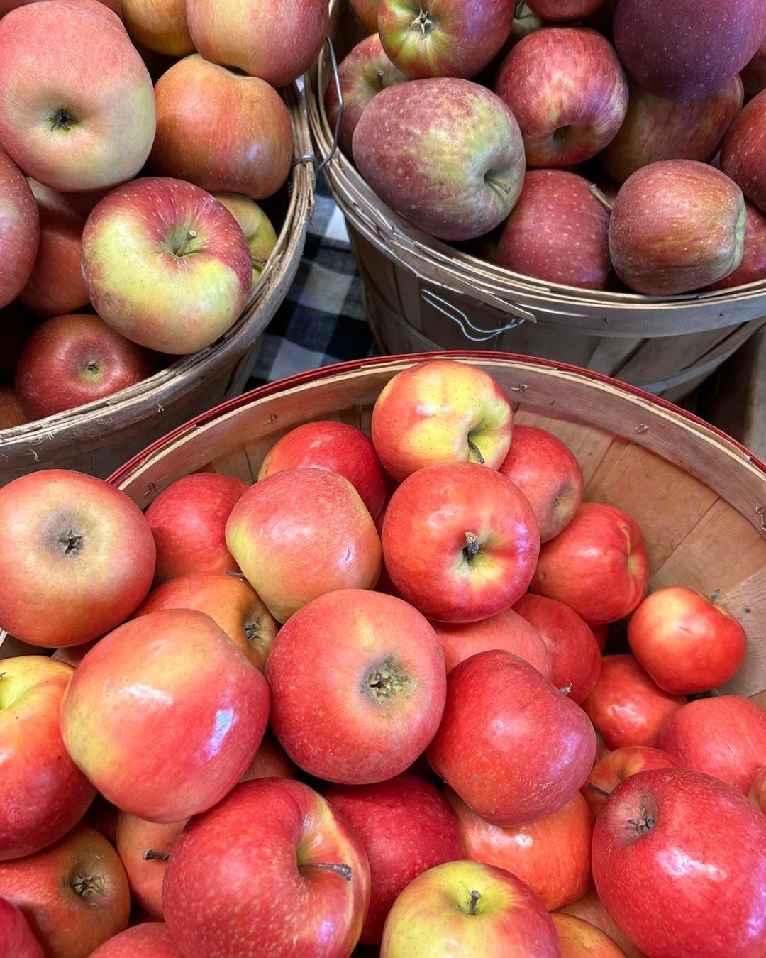 Three baskets filled with red apples are sitting on a table.