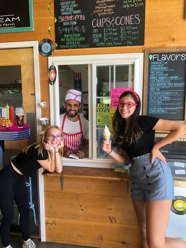 A man and a woman are standing in front of a window holding ice cream cones.