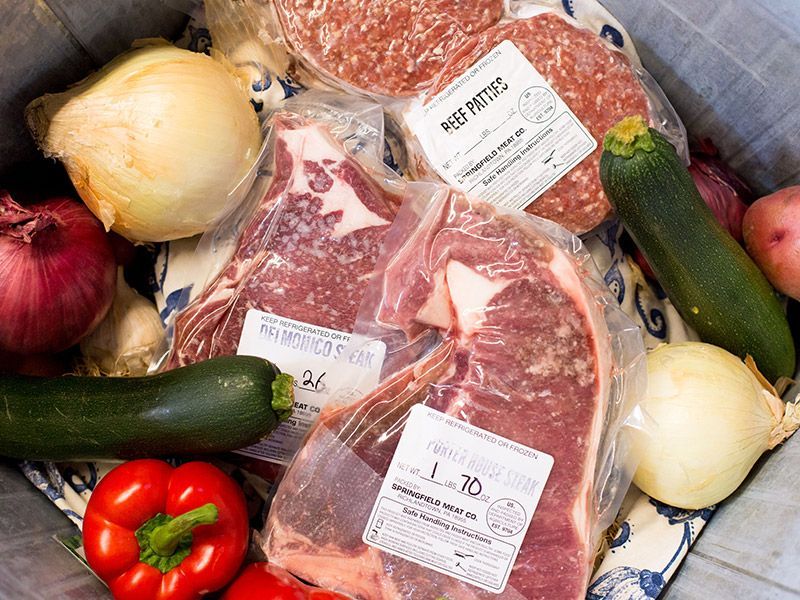 A variety of meats and vegetables are sitting on a table.