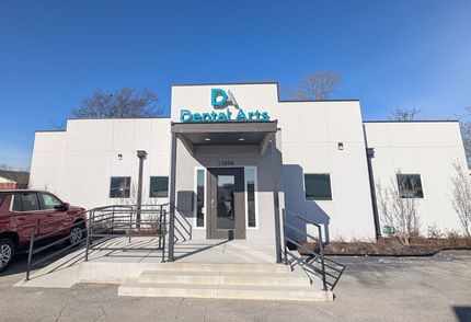 A white building with a blue sign that says da dental arts