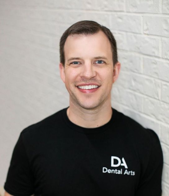 A man wearing a black shirt that says da dental arts
