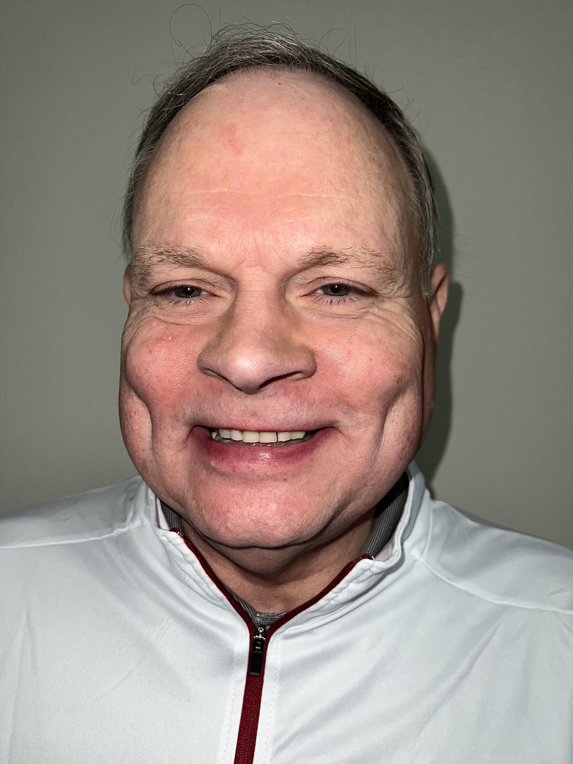 A man in a white shirt is smiling for the camera.