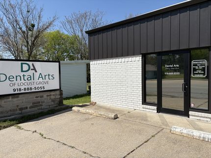 A white brick building with a black roof and a sign that says da dental arts.