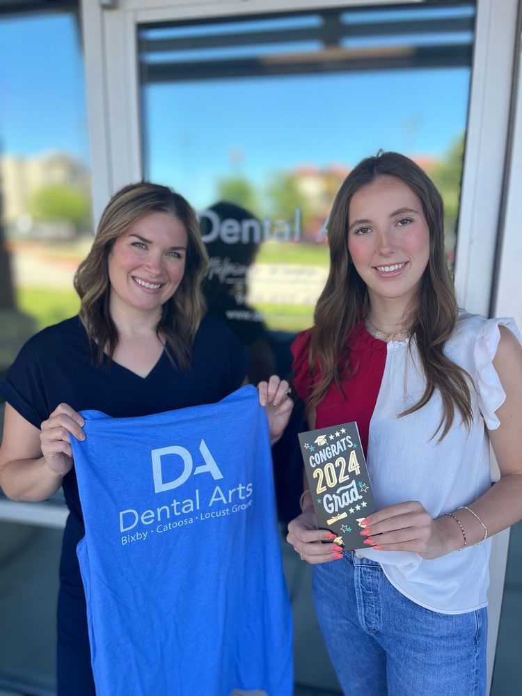 Two women are holding a blue shirt that says dental arts