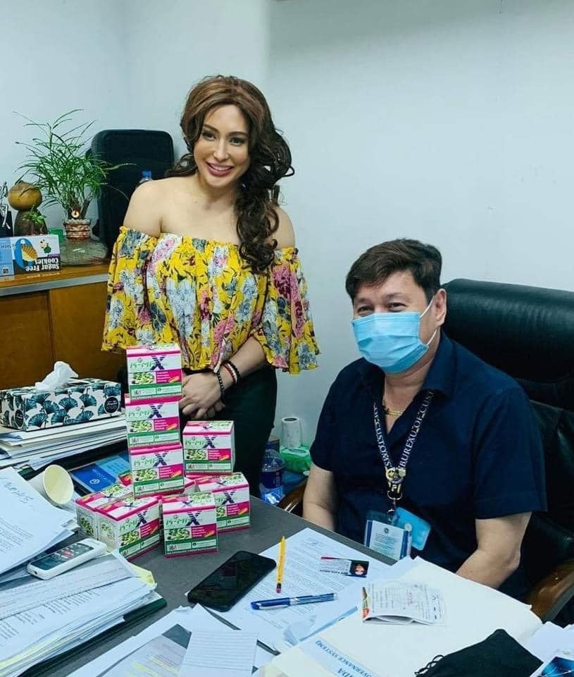 A man and a woman wearing face masks are standing next to each other in an office.