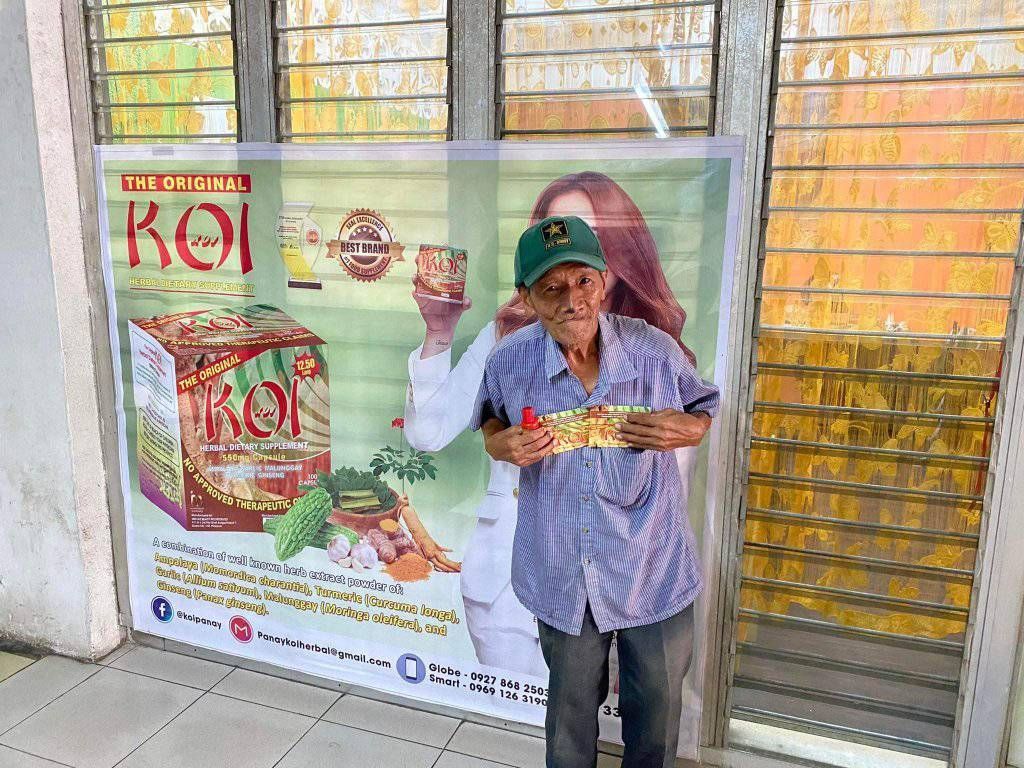 A man is standing in front of a sign holding a box.