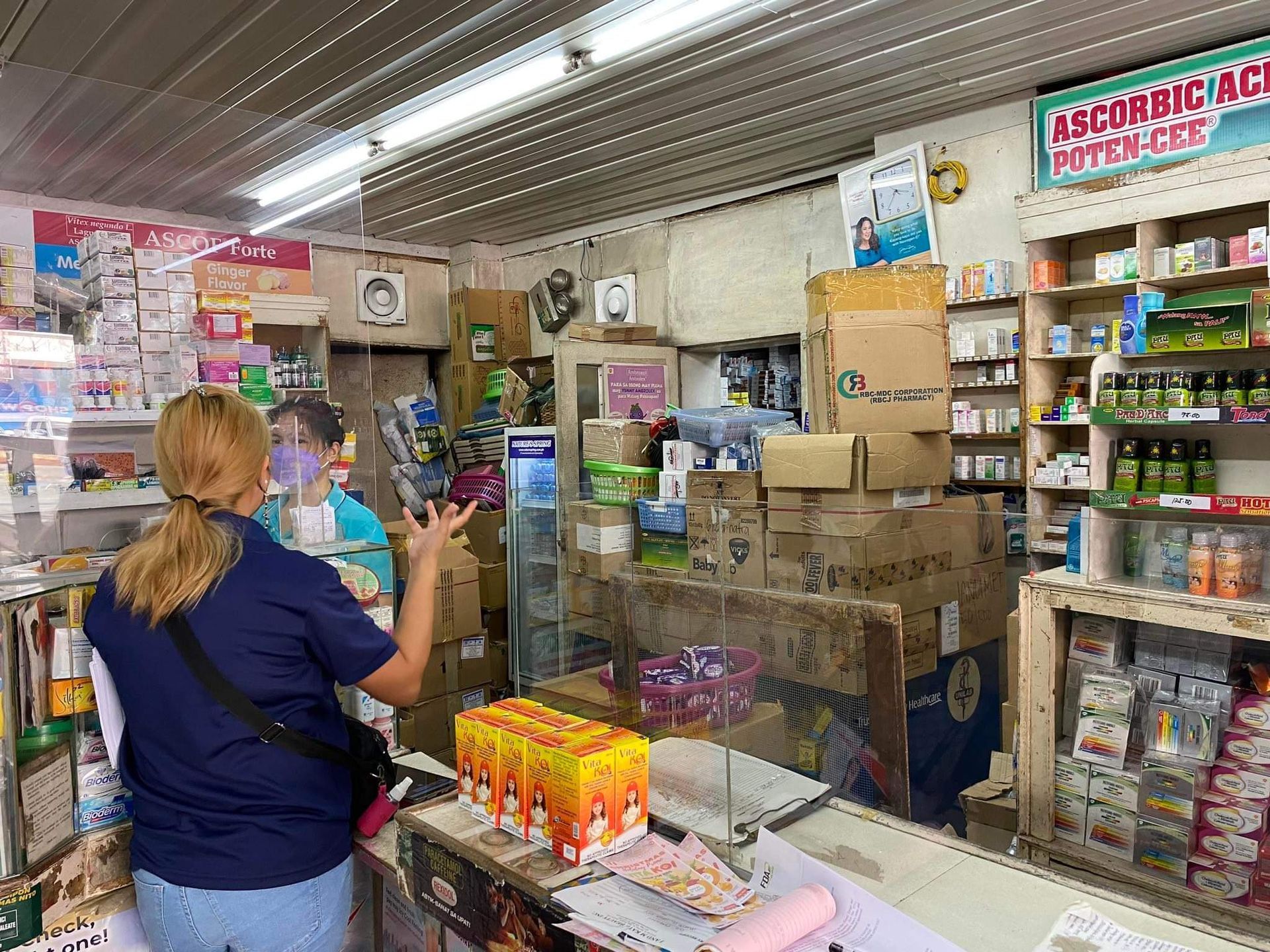 A woman is standing in front of a counter in a pharmacy.
