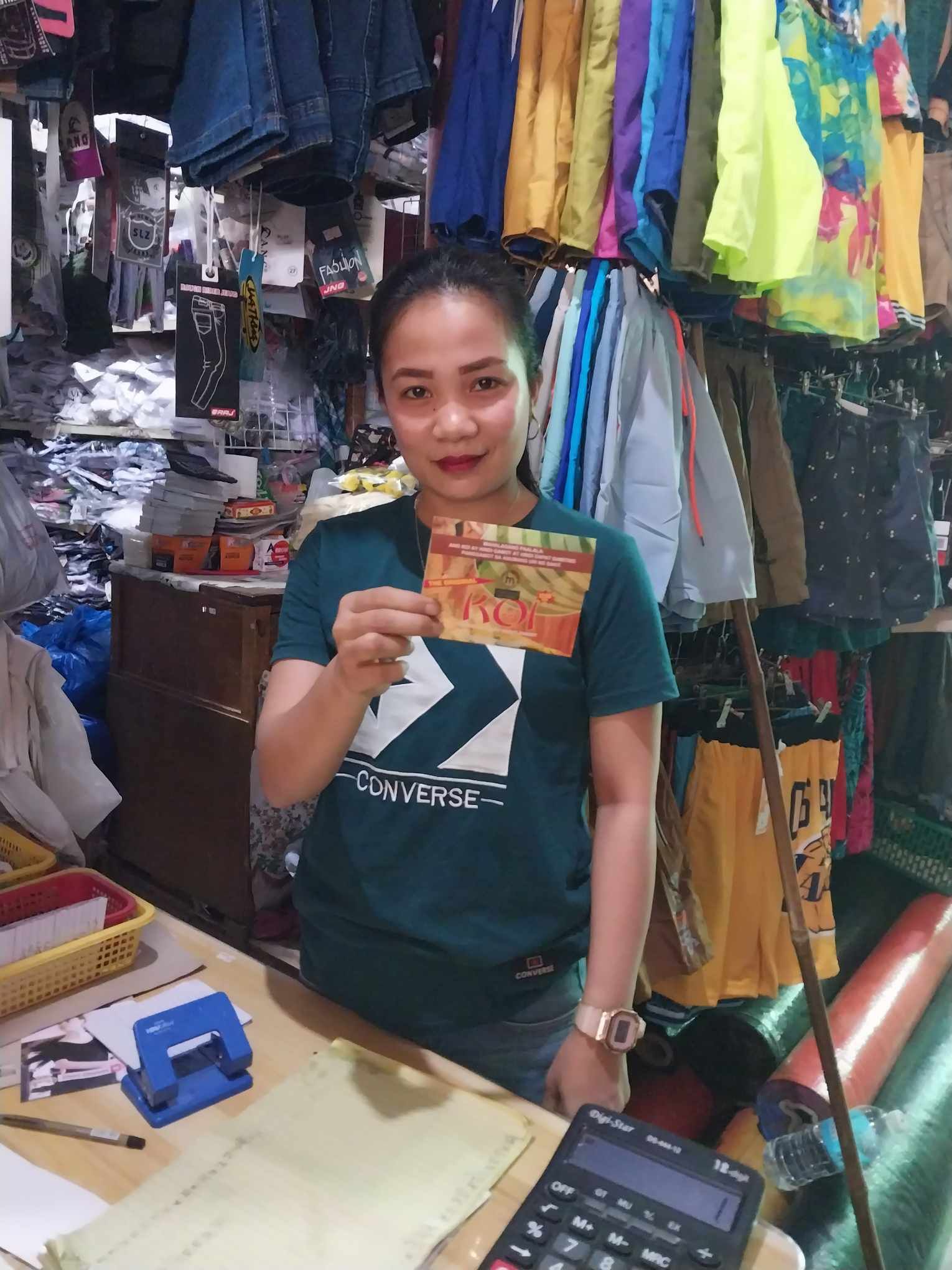 A woman is standing at a counter in a store holding a gift card.