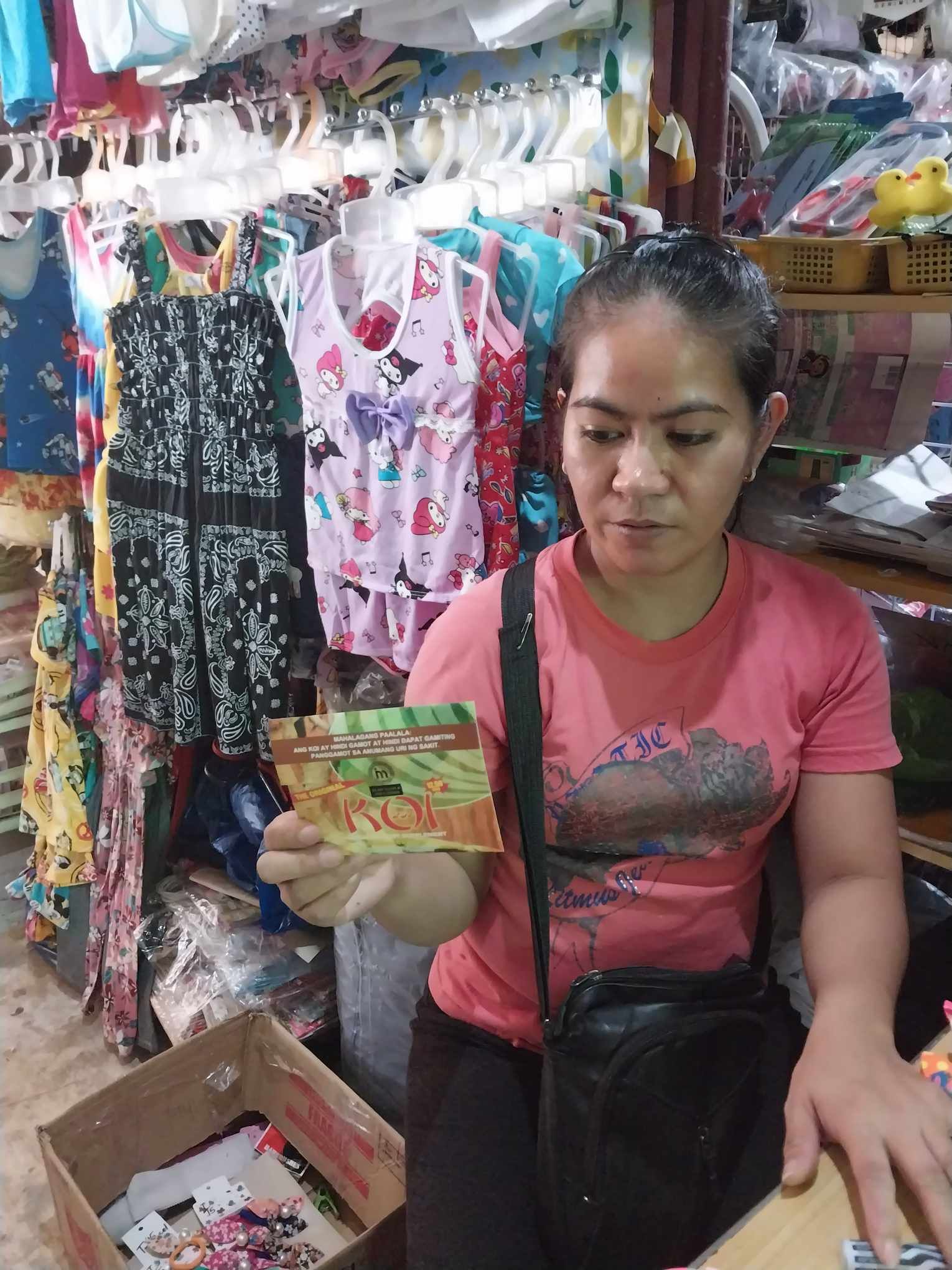 A woman in a pink shirt is holding a card in a store