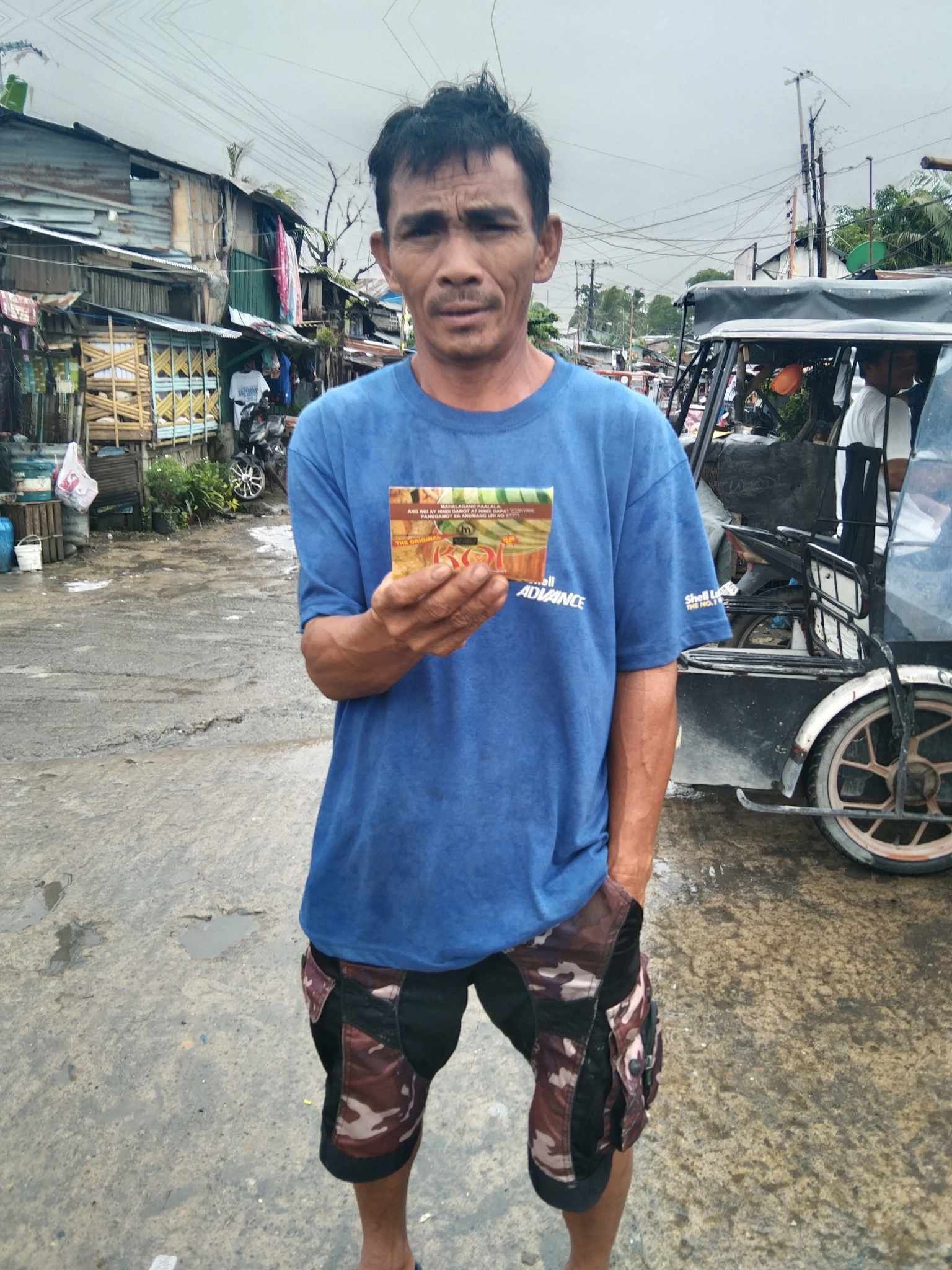 A man in a blue shirt is holding a piece of paper in his hand.