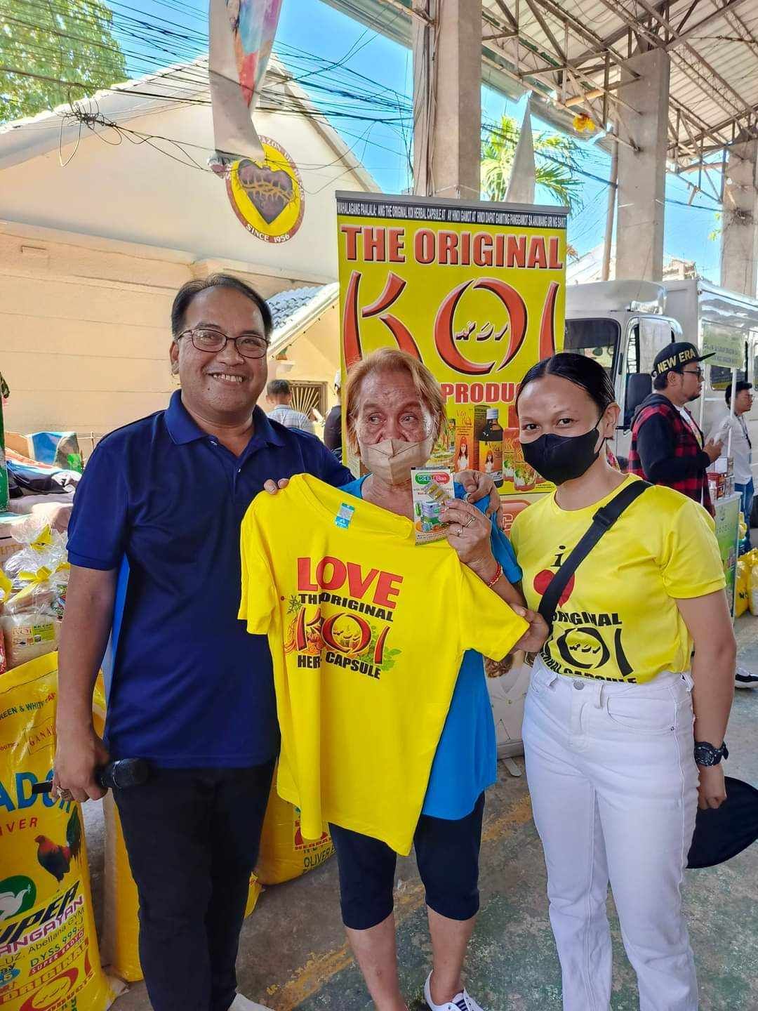 A man and two women are standing next to each other holding a yellow shirt.