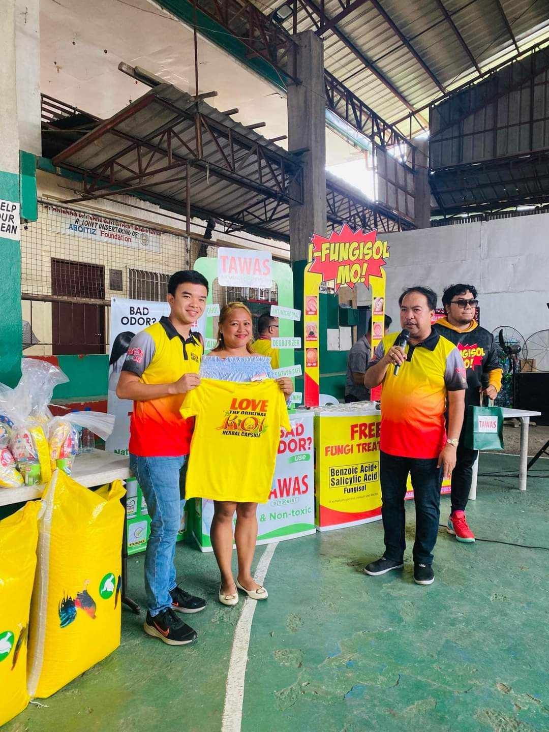 A group of people are standing in a room holding t-shirts.
