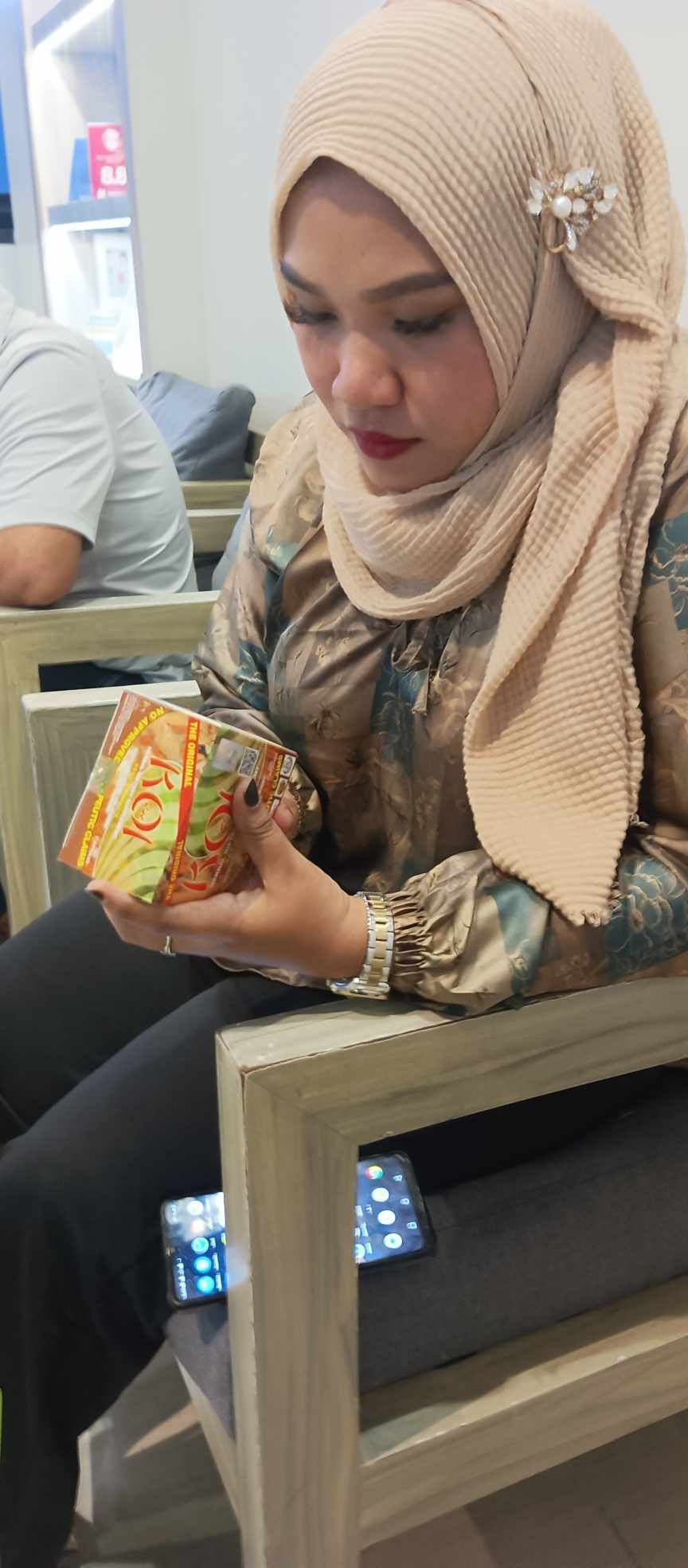 A woman in a hijab is sitting in a chair holding a small bird.